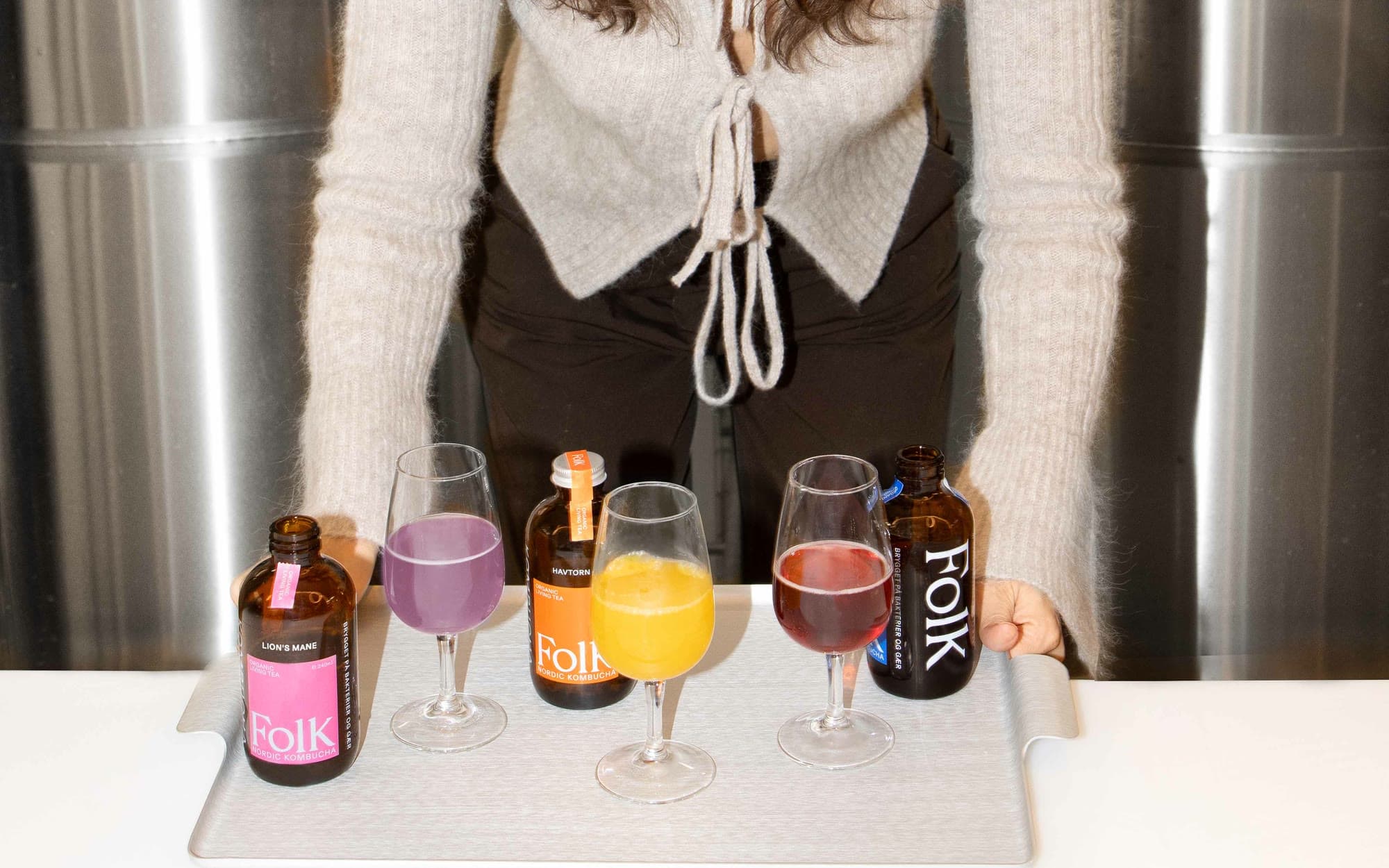 Verkostung in der Brauerei: Flaschen von Folk Kombucha und Gläser mit drei Sorten auf einem Tablett